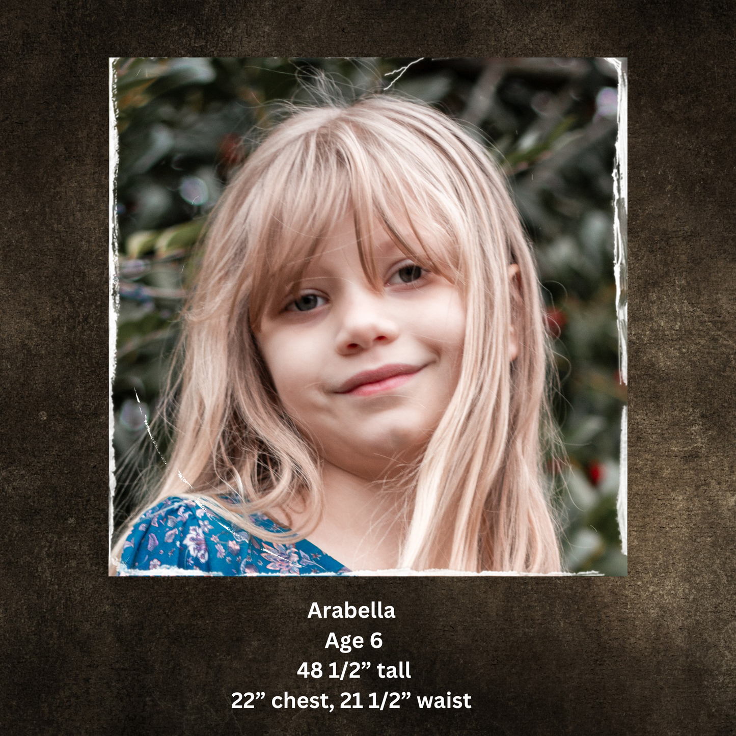 Young girl with blonde hair and a blue floral top, surrounded by greenery.