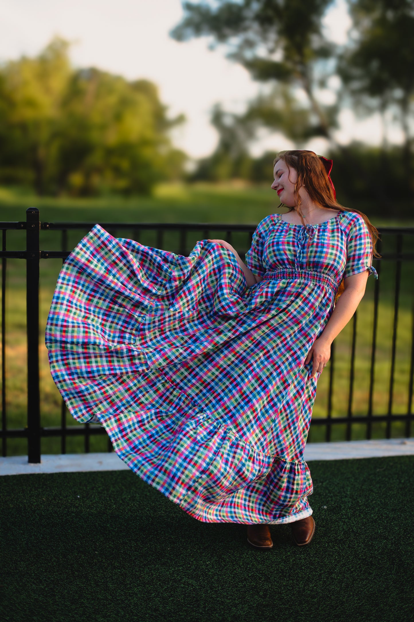 Woman in a colorful plaid modest nursing dress standing outdoors with trees in the background
