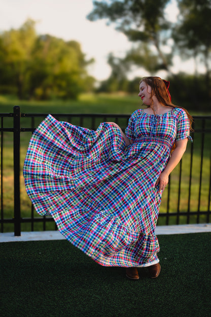 Woman in a colorful plaid modest nursing dress standing outdoors with trees in the background