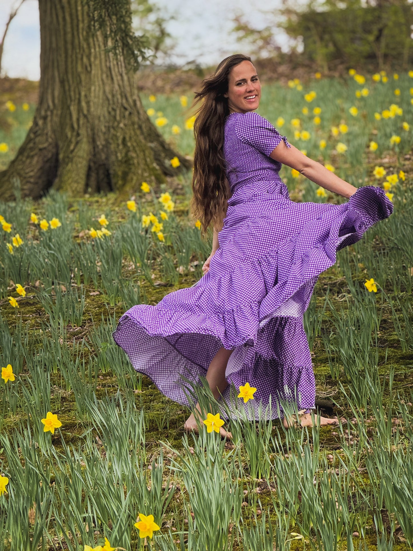 A woman wearing a purple, gingham, five-tiered maxi modest nursing dress