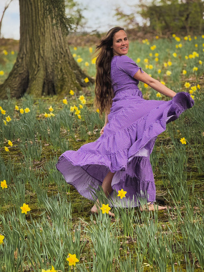 A woman wearing a purple, gingham, five-tiered maxi modest nursing dress