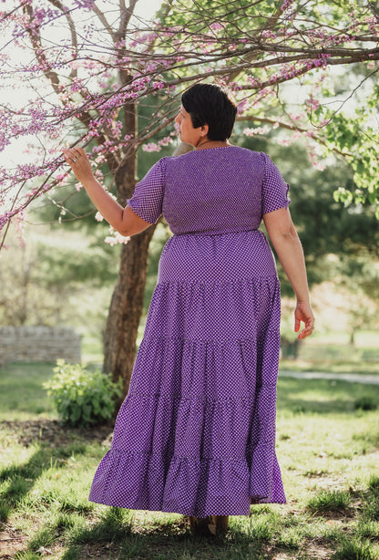 A woman wearing a purple, gingham, five-tiered maxi modest nursing dress