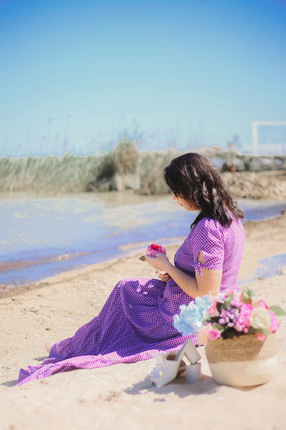 A woman wearing a purple, gingham, five-tiered maxi modest nursing dress