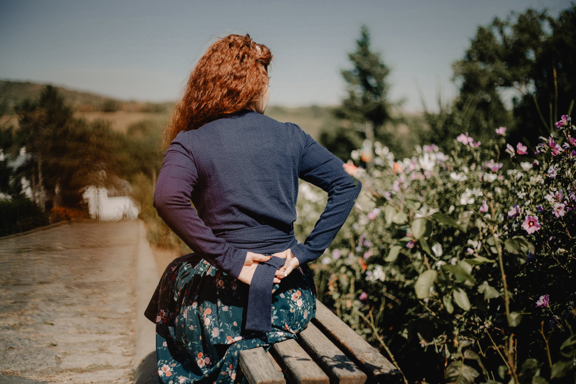 Person with red hair sitting on wooden bench outdoors
