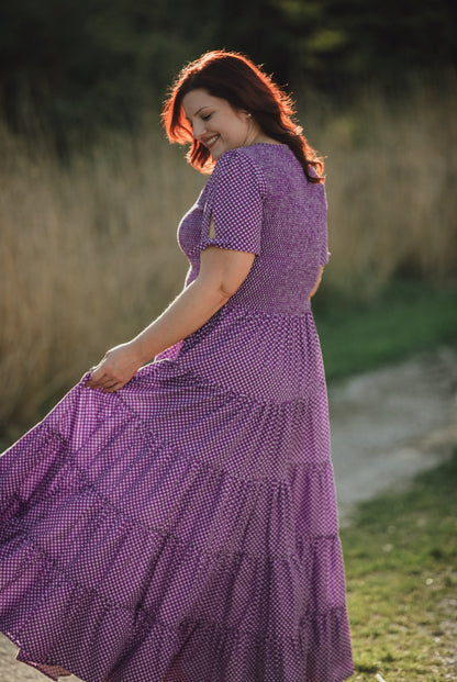 A woman wearing a purple, gingham, five-tiered maxi modest nursing dress