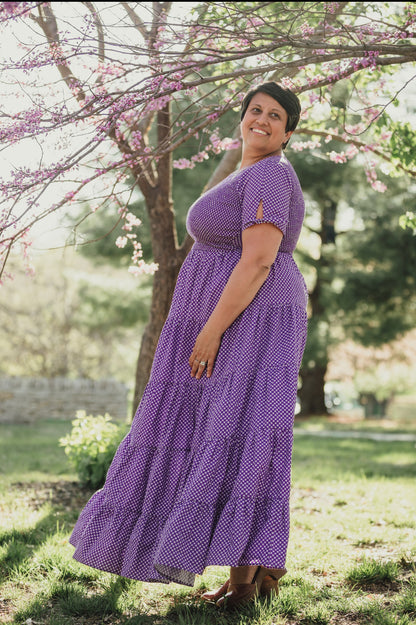 A woman wearing a purple, gingham, five-tiered maxi modest nursing dress