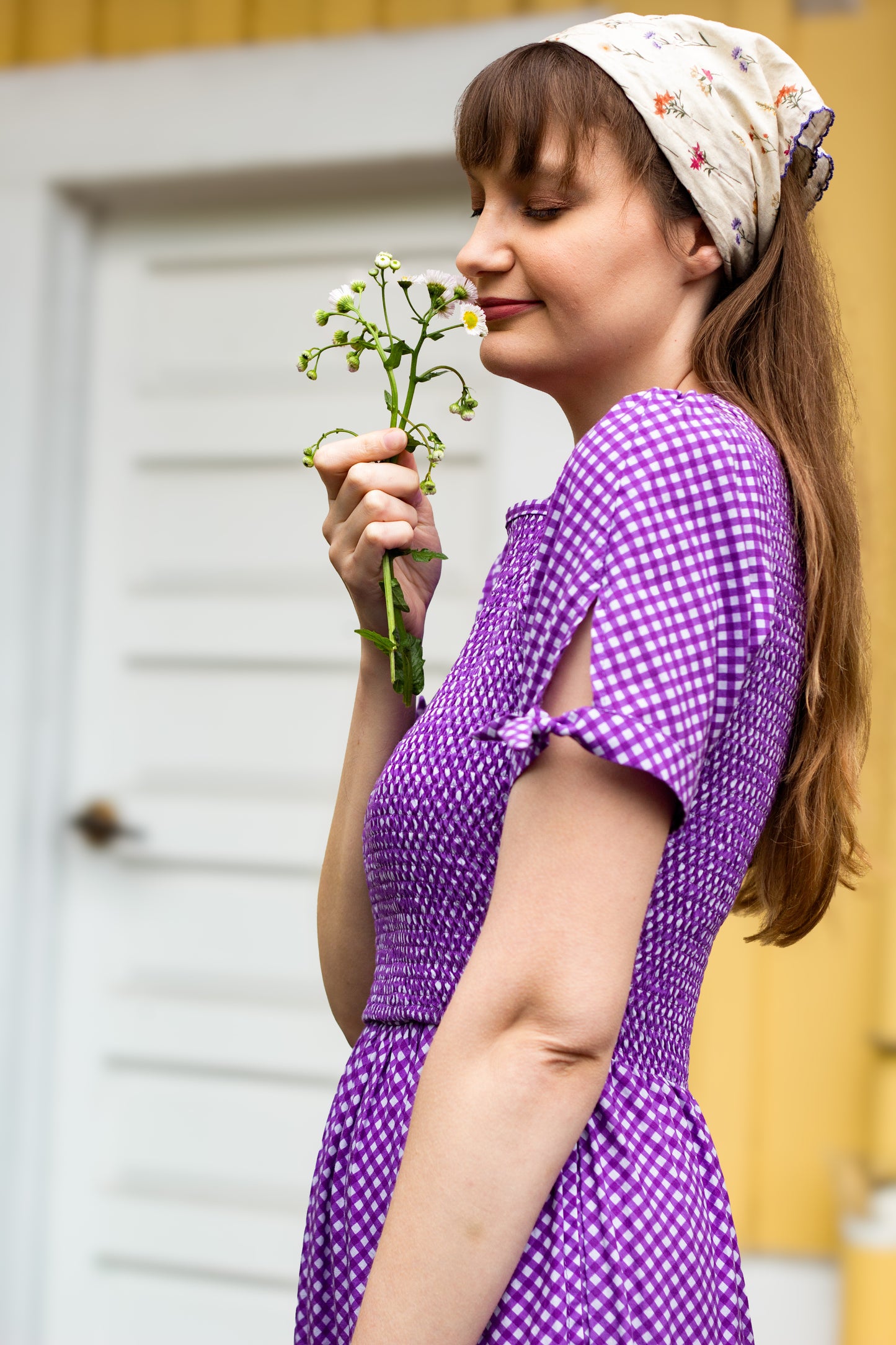 A woman wearing a purple, gingham, five-tiered maxi modest nursing dress