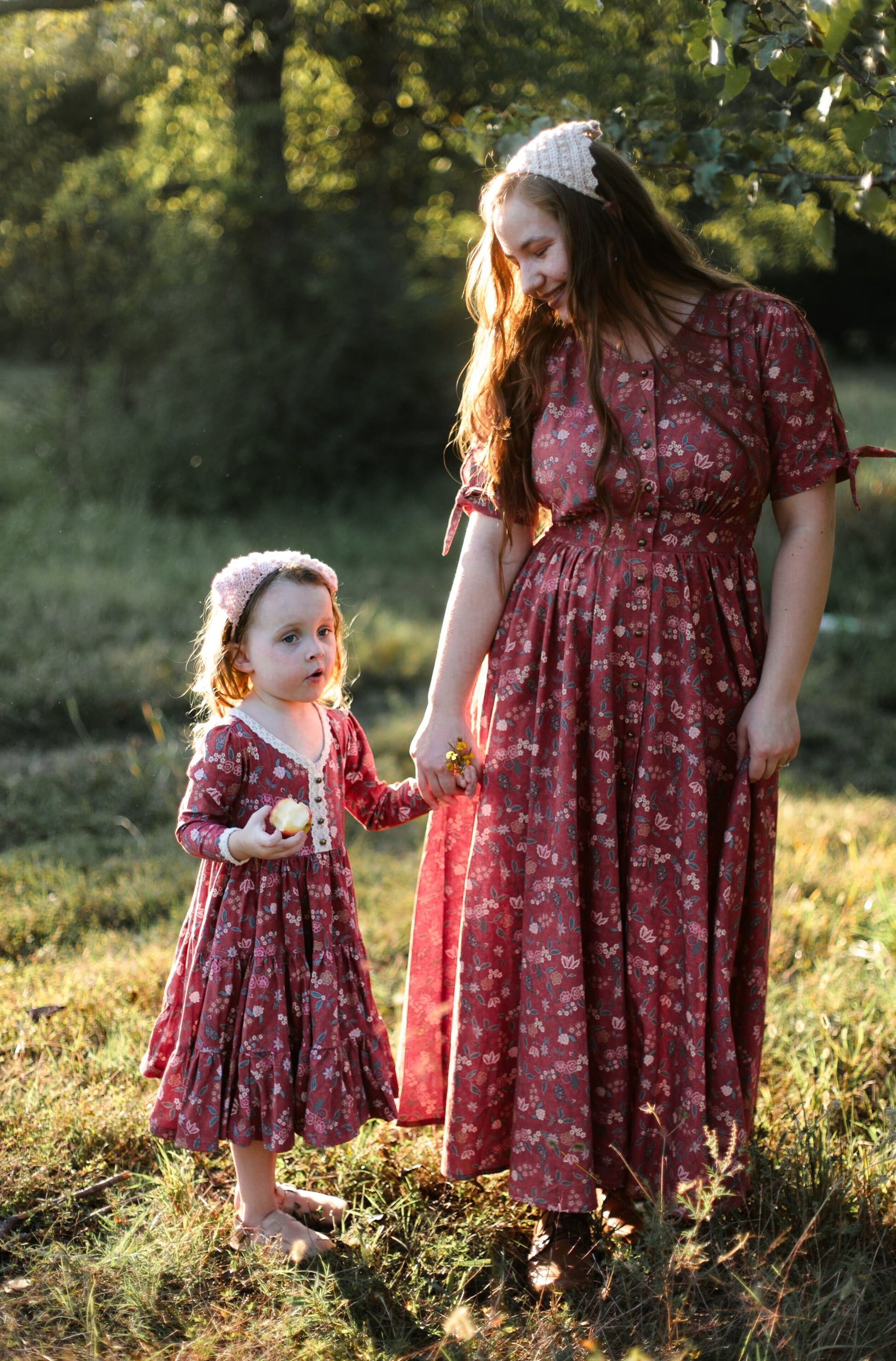 Mother in modest nursing dress with child in matching floral dress outdoors