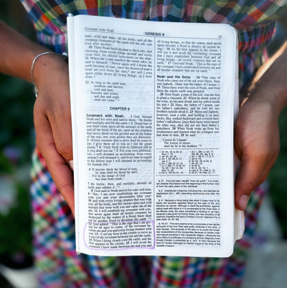 Woman holding a Bible open to Genesis 9 wearing a modest nursing dress