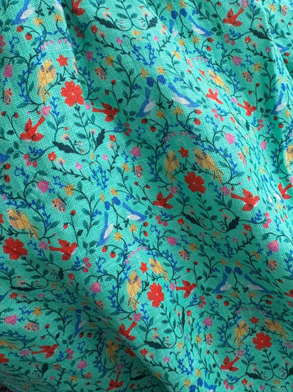 Close-up of fabric with colorful floral and bird pattern on a teal background