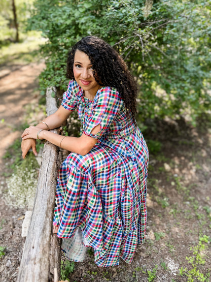 Woman in a colorful modest nursing dress sitting on a wooden log in a natural setting