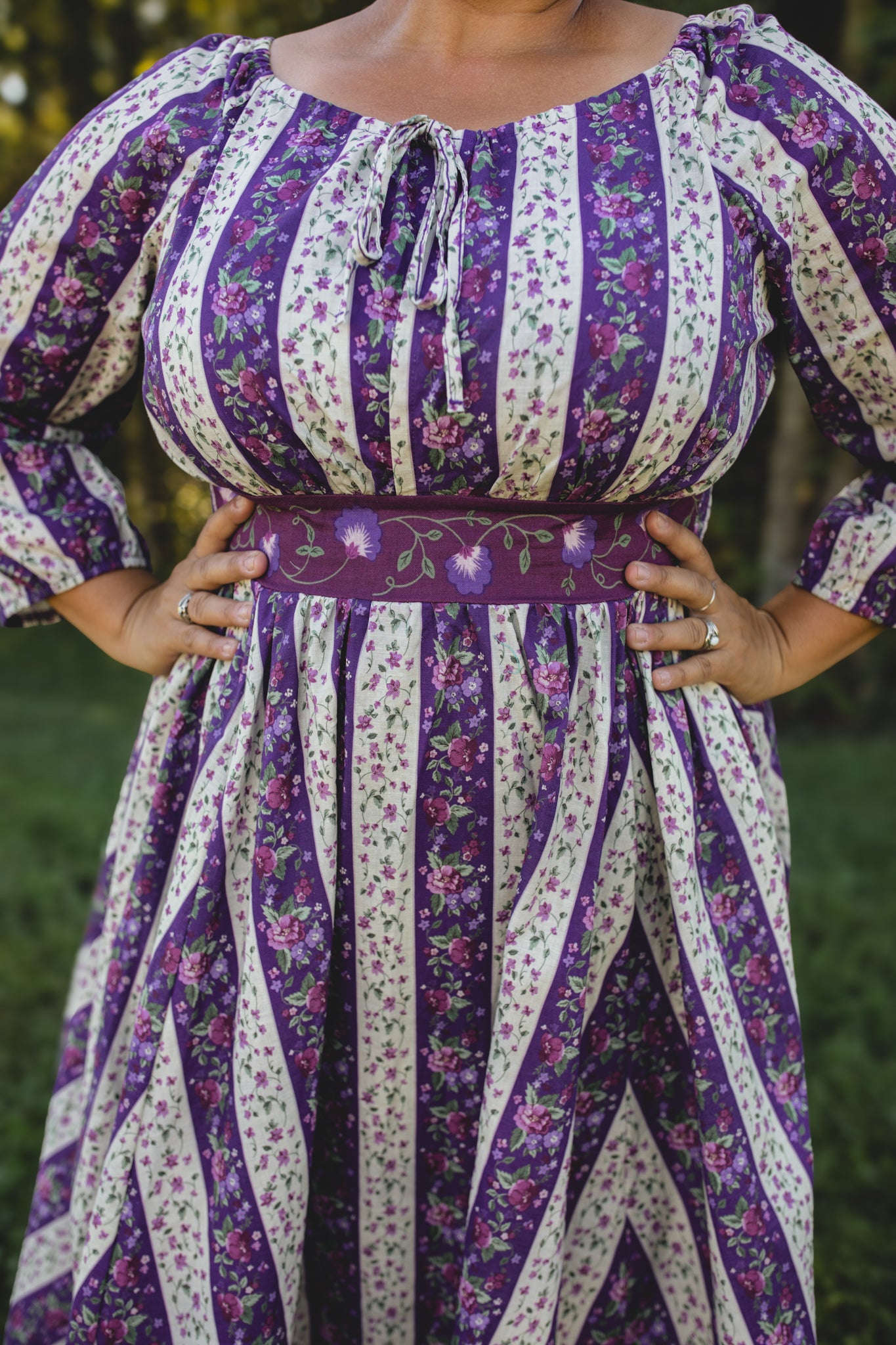 Modest nursing woman wearing purple floral dress outdoors