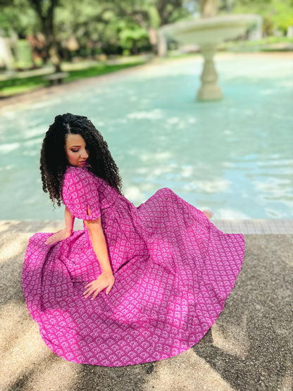 Woman in a pink modest nursing dress sitting by a fountain in a park
