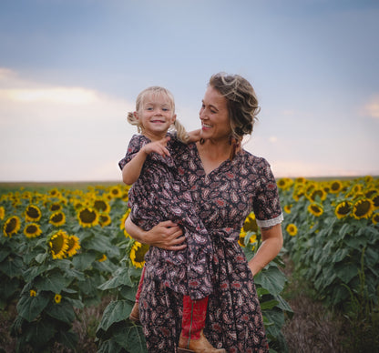 woman in a modest nursing dress, holding child in sunflower field