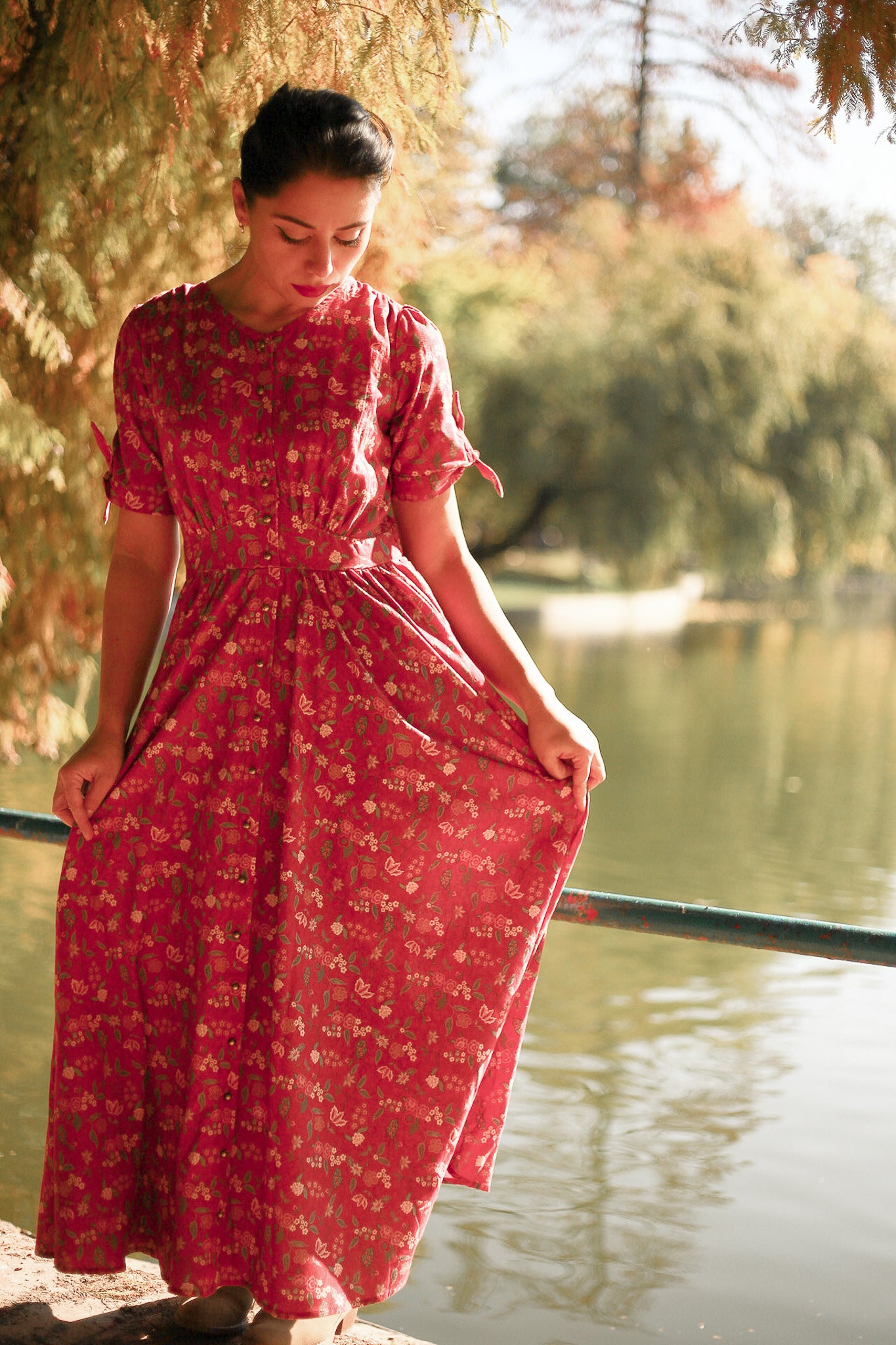 Woman in modest nursing red floral dress by lake