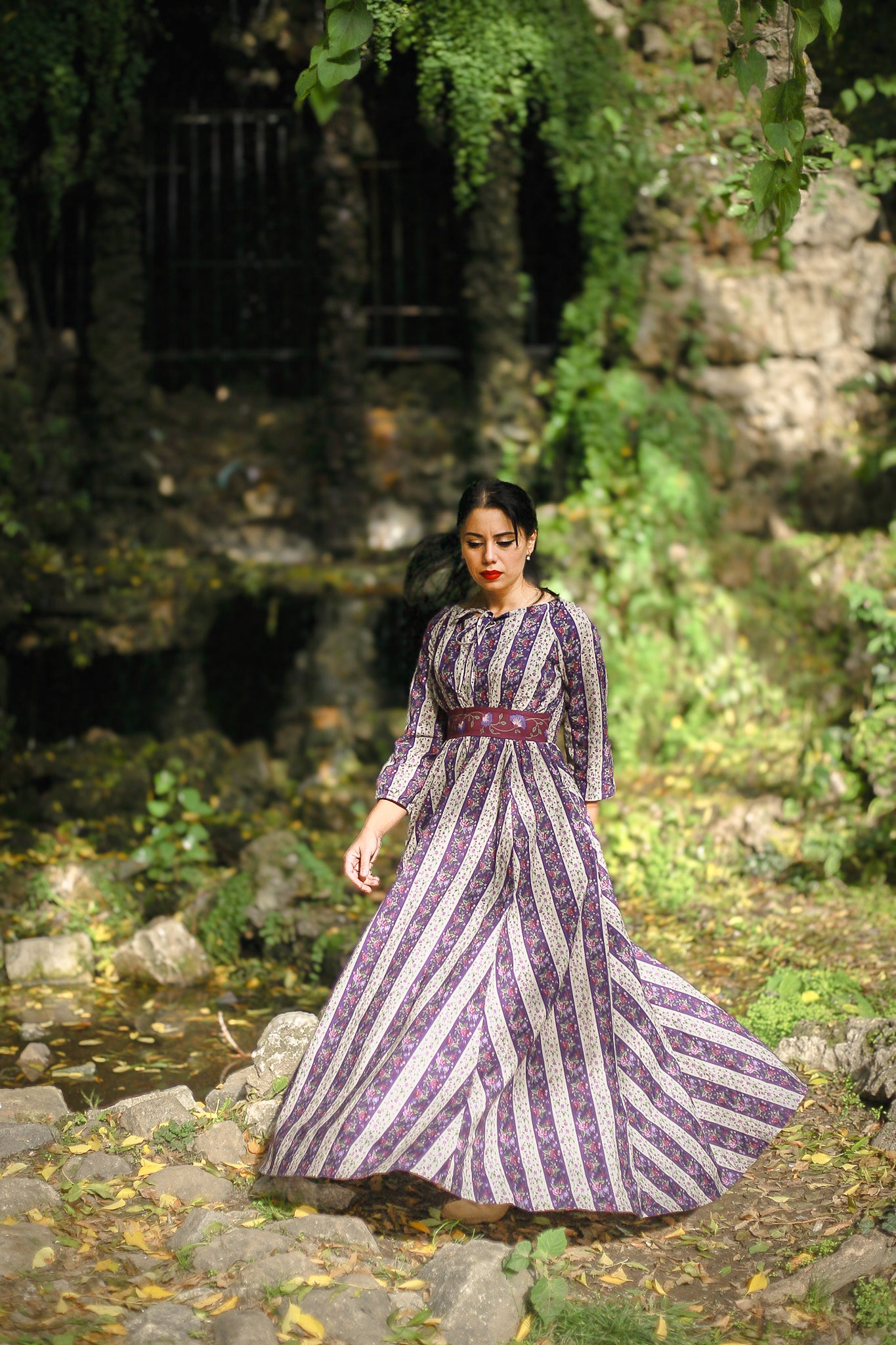 Modest nursing woman in long striped dress in natural setting