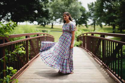 Woman in a colorful modest nursing dress standing on a wooden bridge in a park