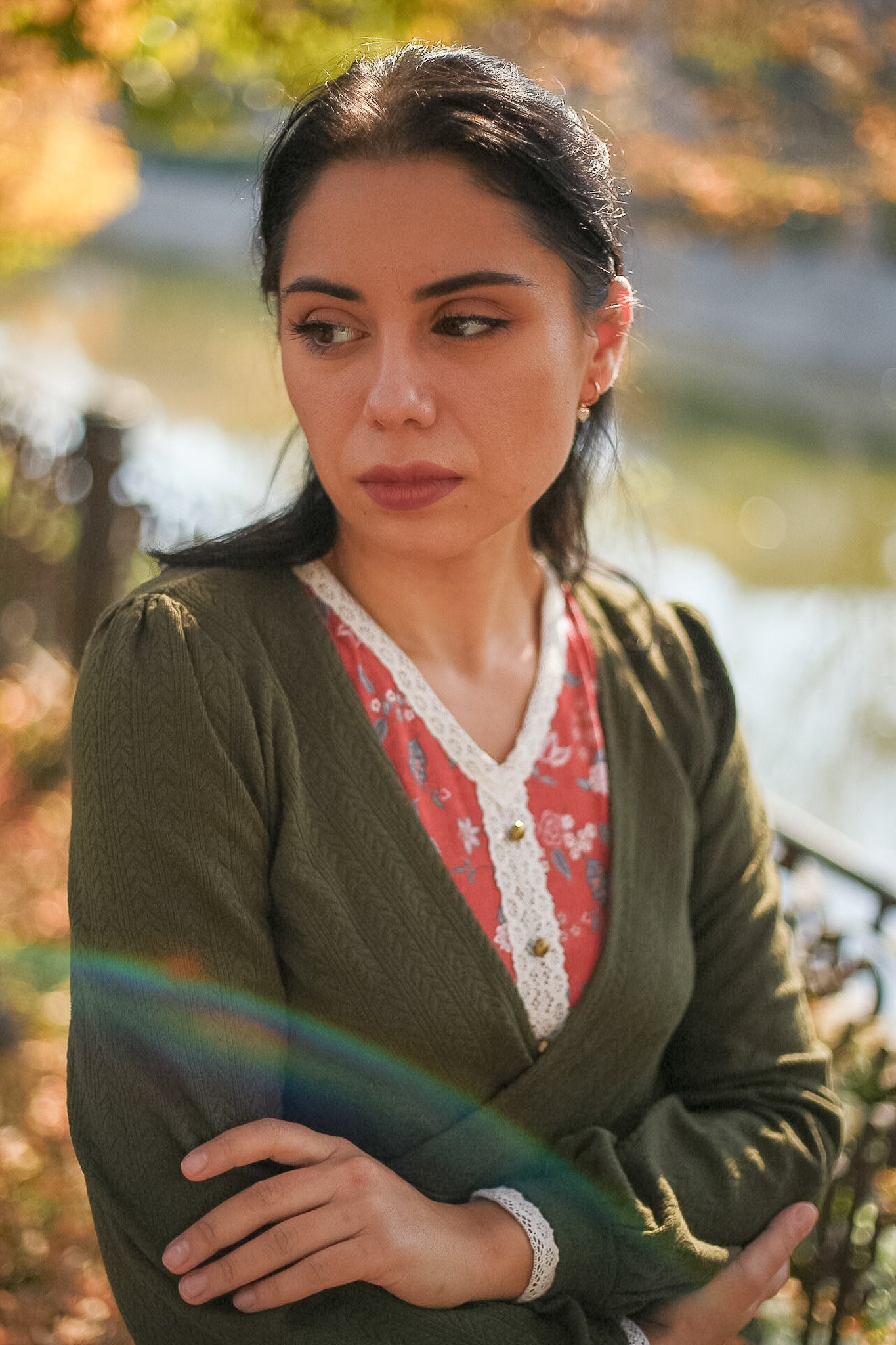 Woman wearing green cardigan over red lace blouse outdoors