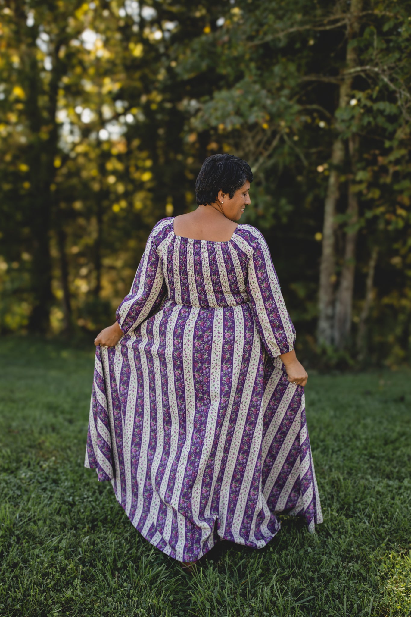 Modest nursing woman in purple striped dress in grassy area