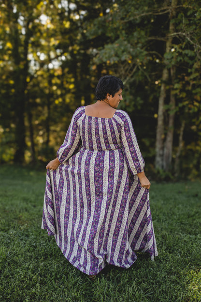 Modest nursing woman in purple striped dress in grassy area