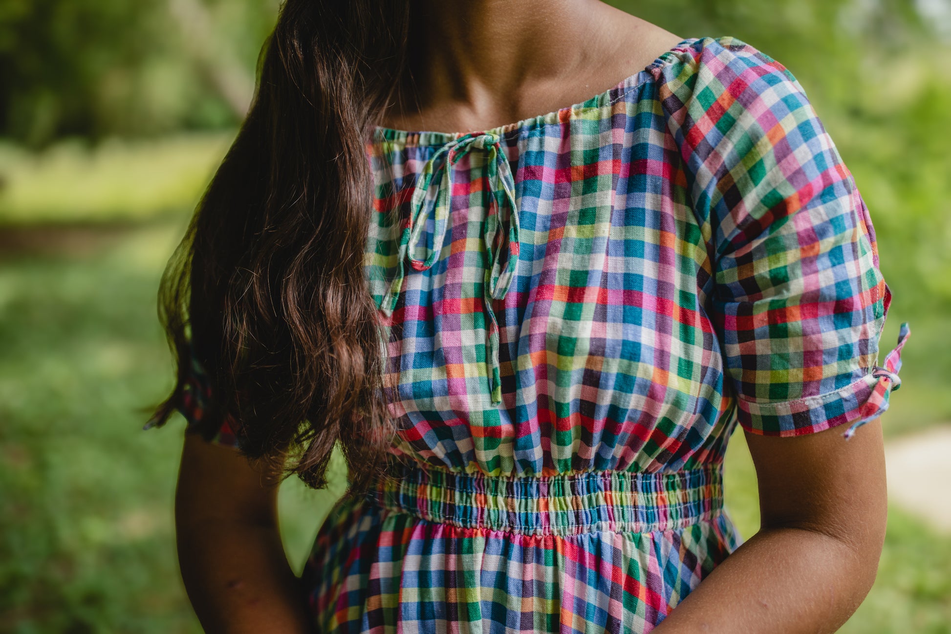 Person wearing a colorful checkered modest nursing dress in a natural setting