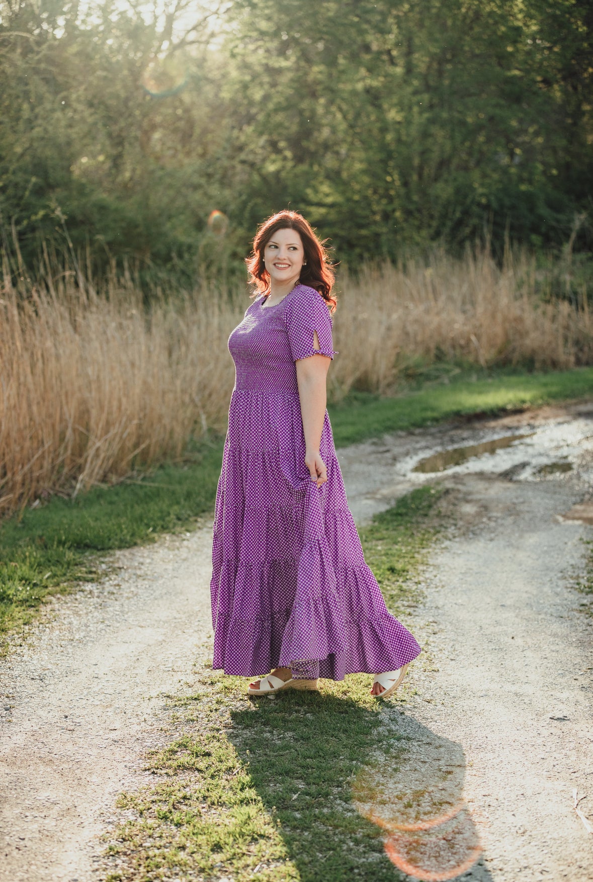 A woman wearing a purple, gingham, five-tiered maxi modest nursing dress