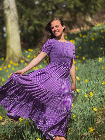 A woman wearing a purple, gingham, five-tiered maxi modest nursing dress