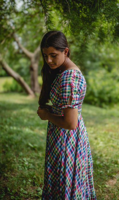 Woman in a colorful modest nursing dress standing in a green, natural setting