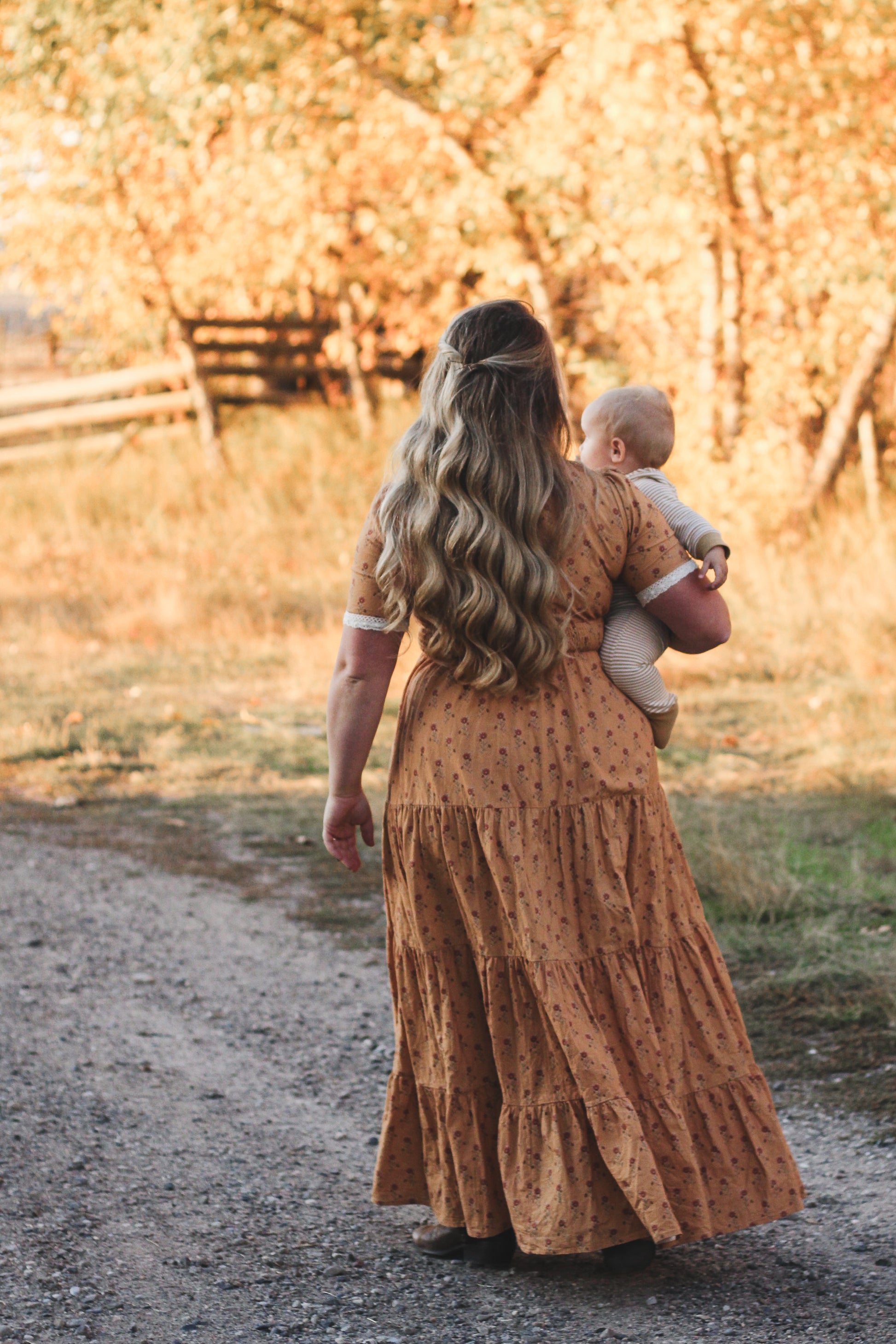 Woman in modest nursing dress holding baby outdoors