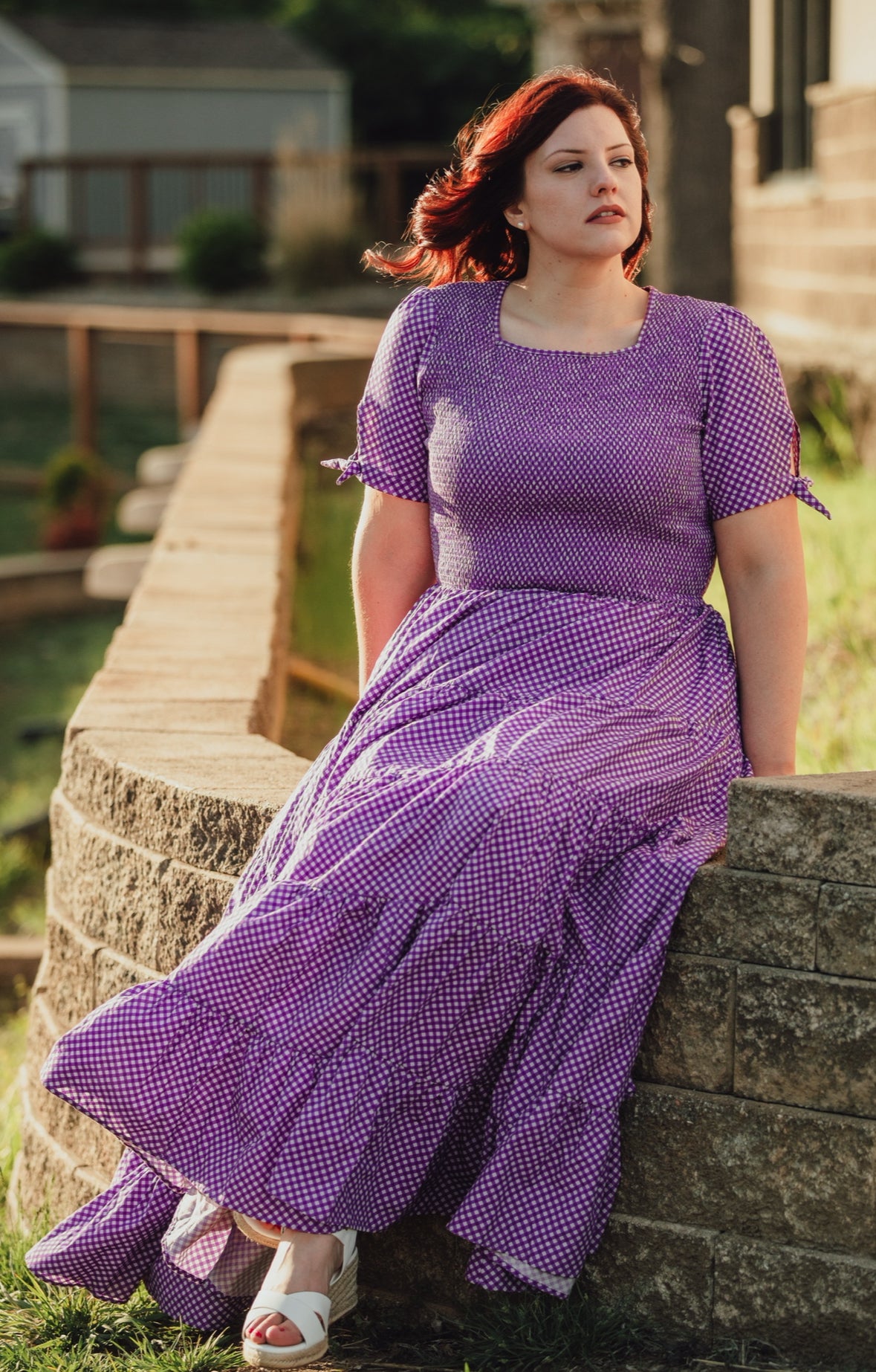 A woman wearing a purple, gingham, five-tiered maxi modest nursing dress