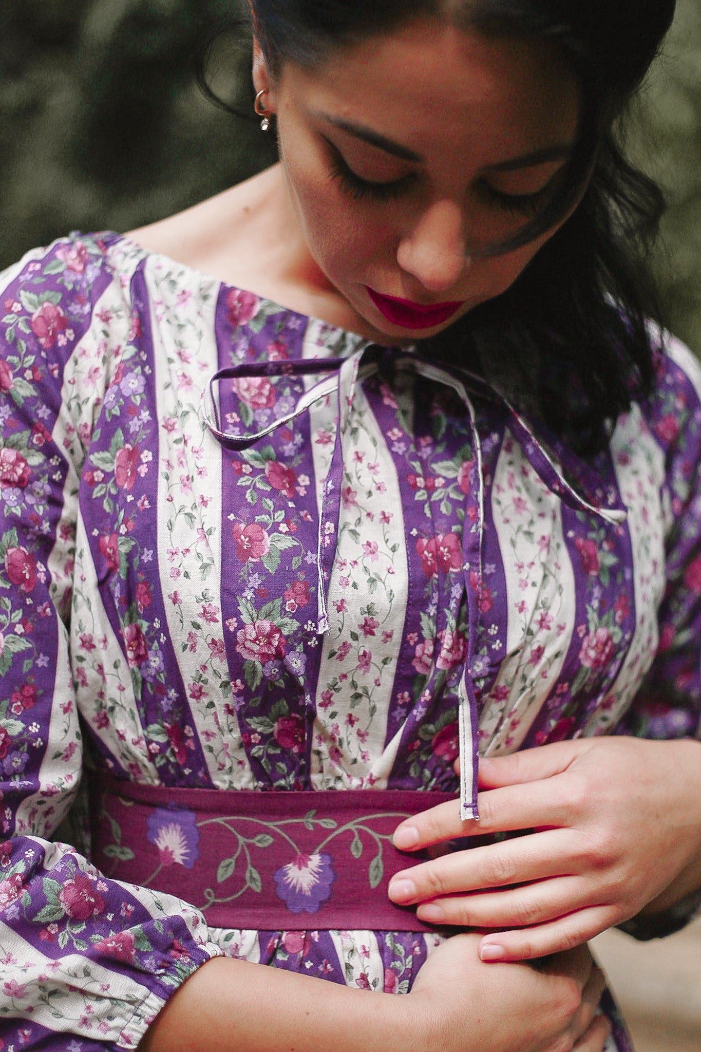 Modest nursing woman wearing purple floral dress with belt outdoors
