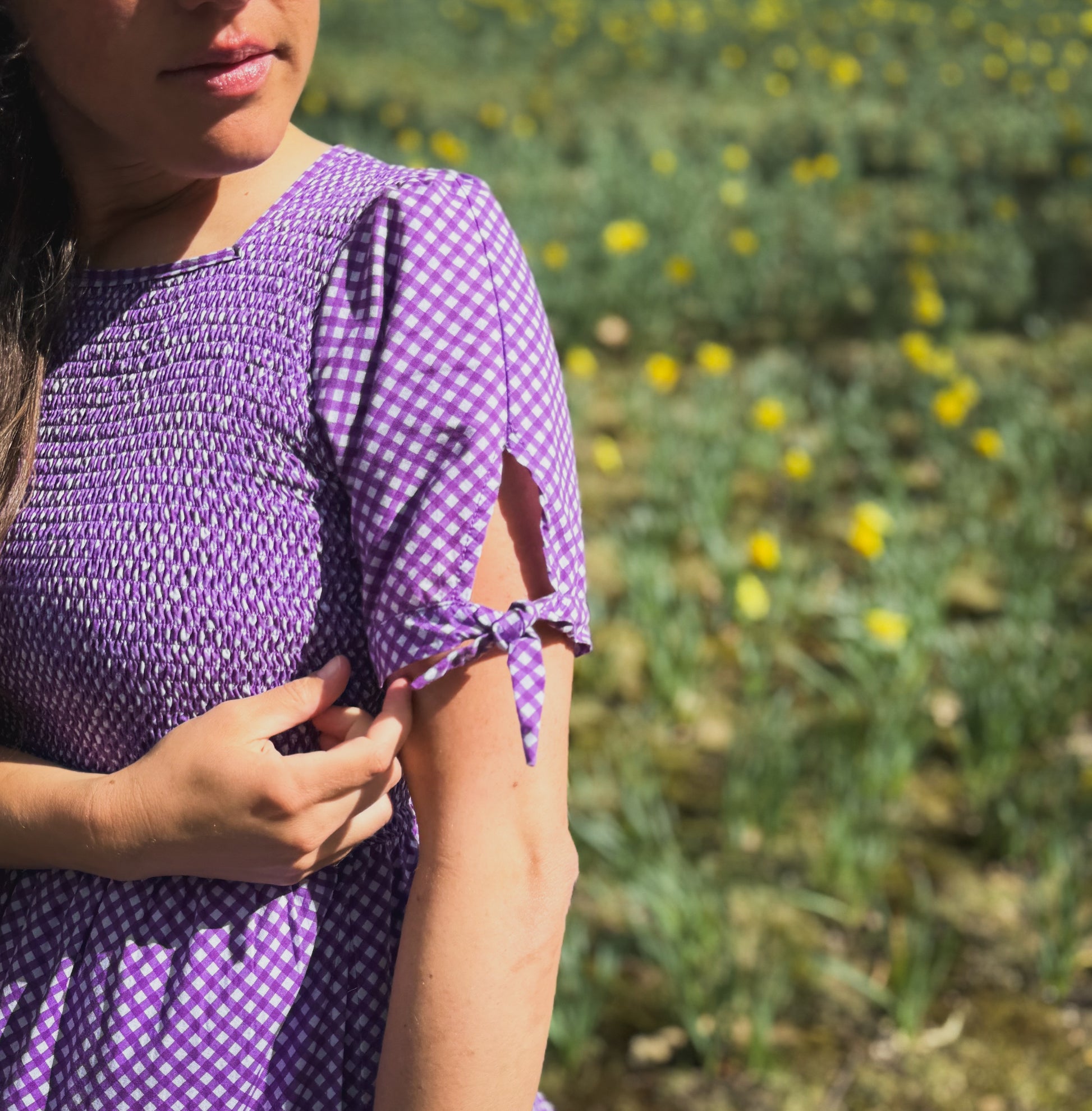 A woman wearing a purple, gingham, five-tiered maxi modest nursing dress