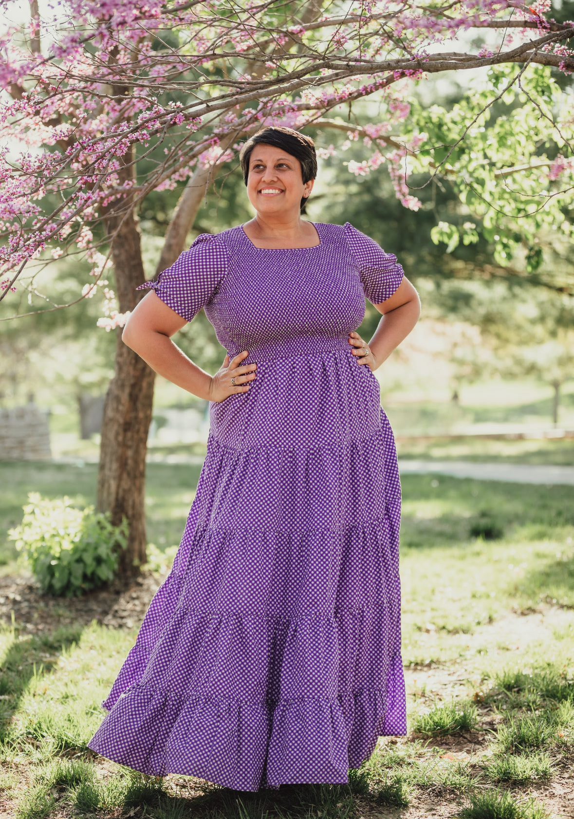 A woman wearing a purple, gingham, five-tiered maxi modest nursing dress