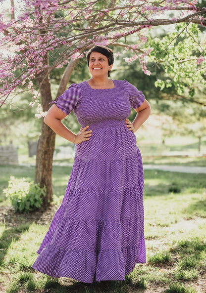 A woman wearing a purple, gingham, five-tiered maxi modest nursing dress