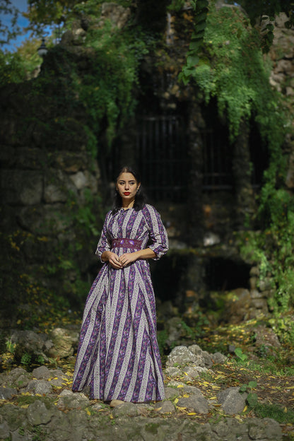 Modest nursing woman in purple striped dress among stone ruins