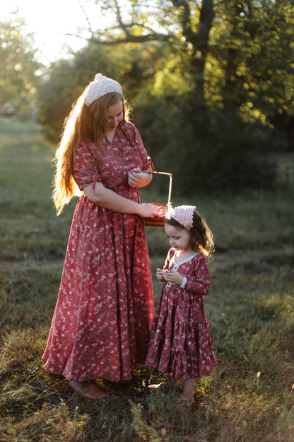 Modest nursing woman and child in matching red floral dresses outdoors