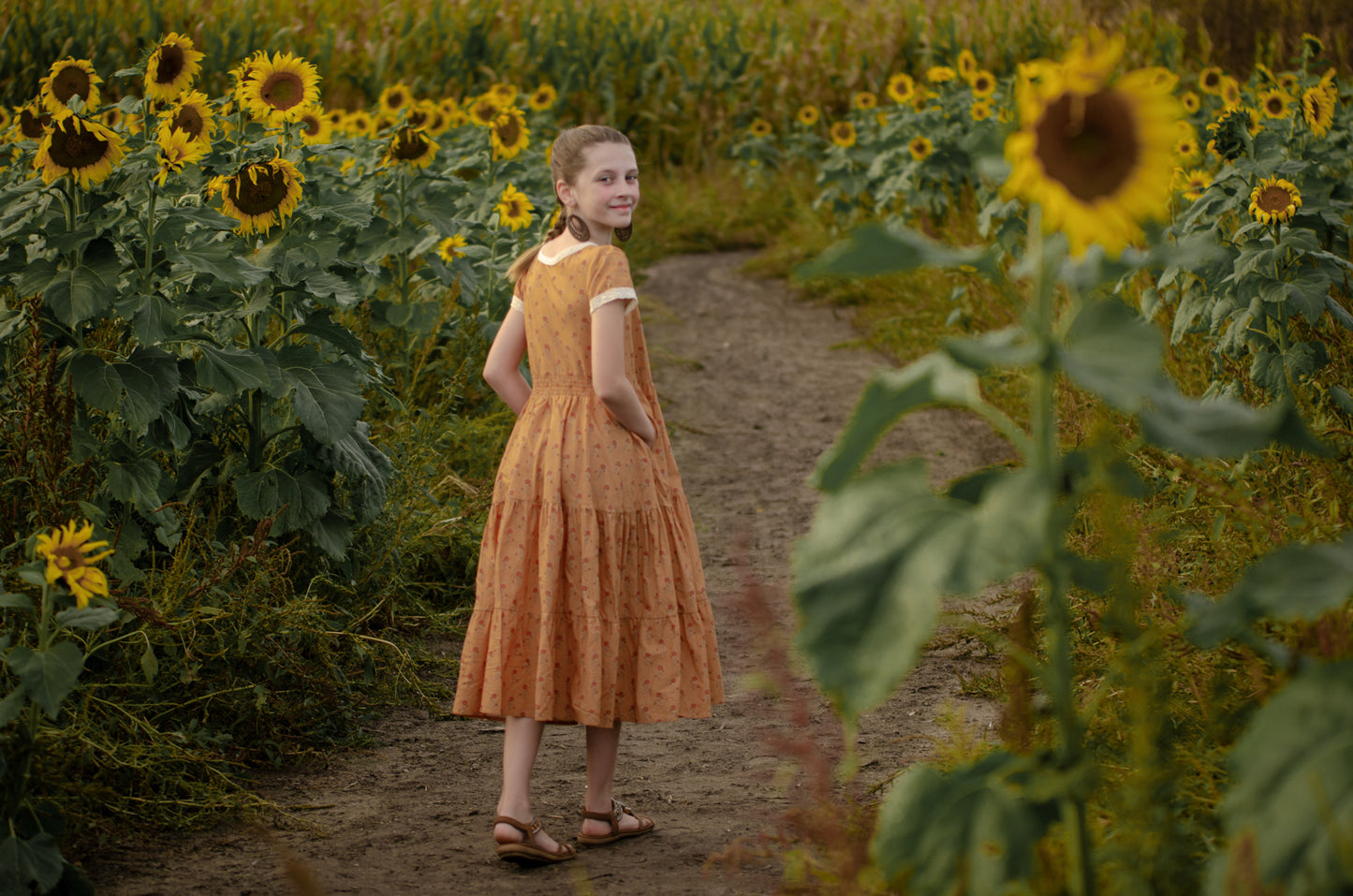 Young girl in modest dress in sunflower field