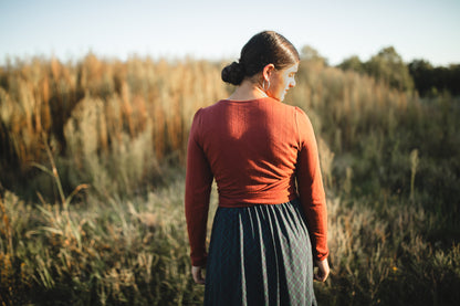 Woman in red sweater and dark skirt outdoors