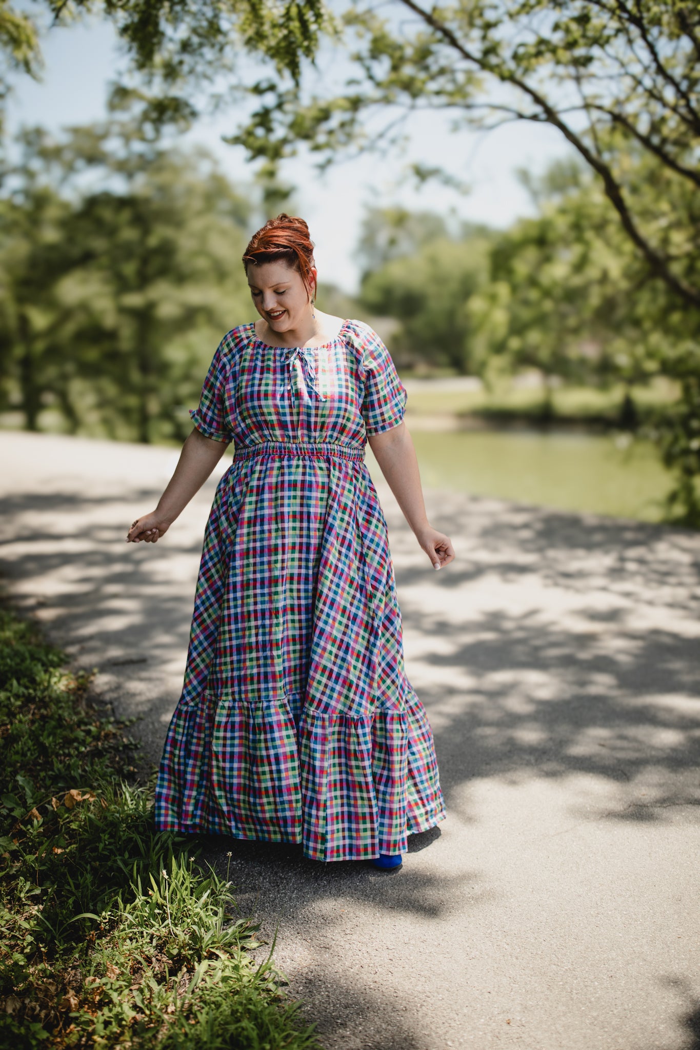 Woman in a plaid modest nursing dress walking on a path in a park