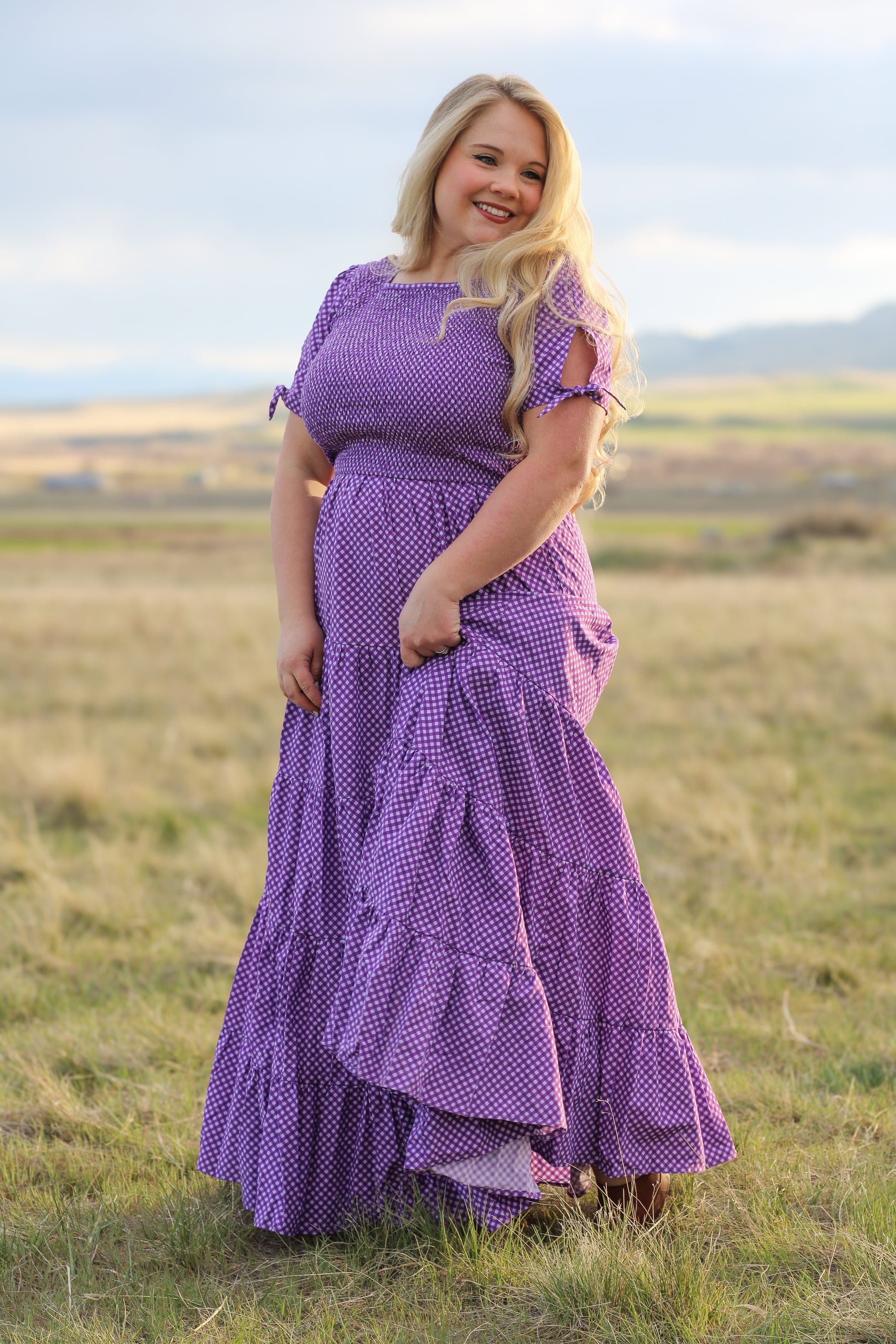 A woman wearing a purple, gingham, five-tiered maxi modest nursing dress