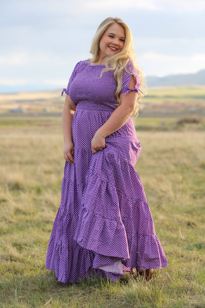 A woman wearing a purple, gingham, five-tiered maxi modest nursing dress