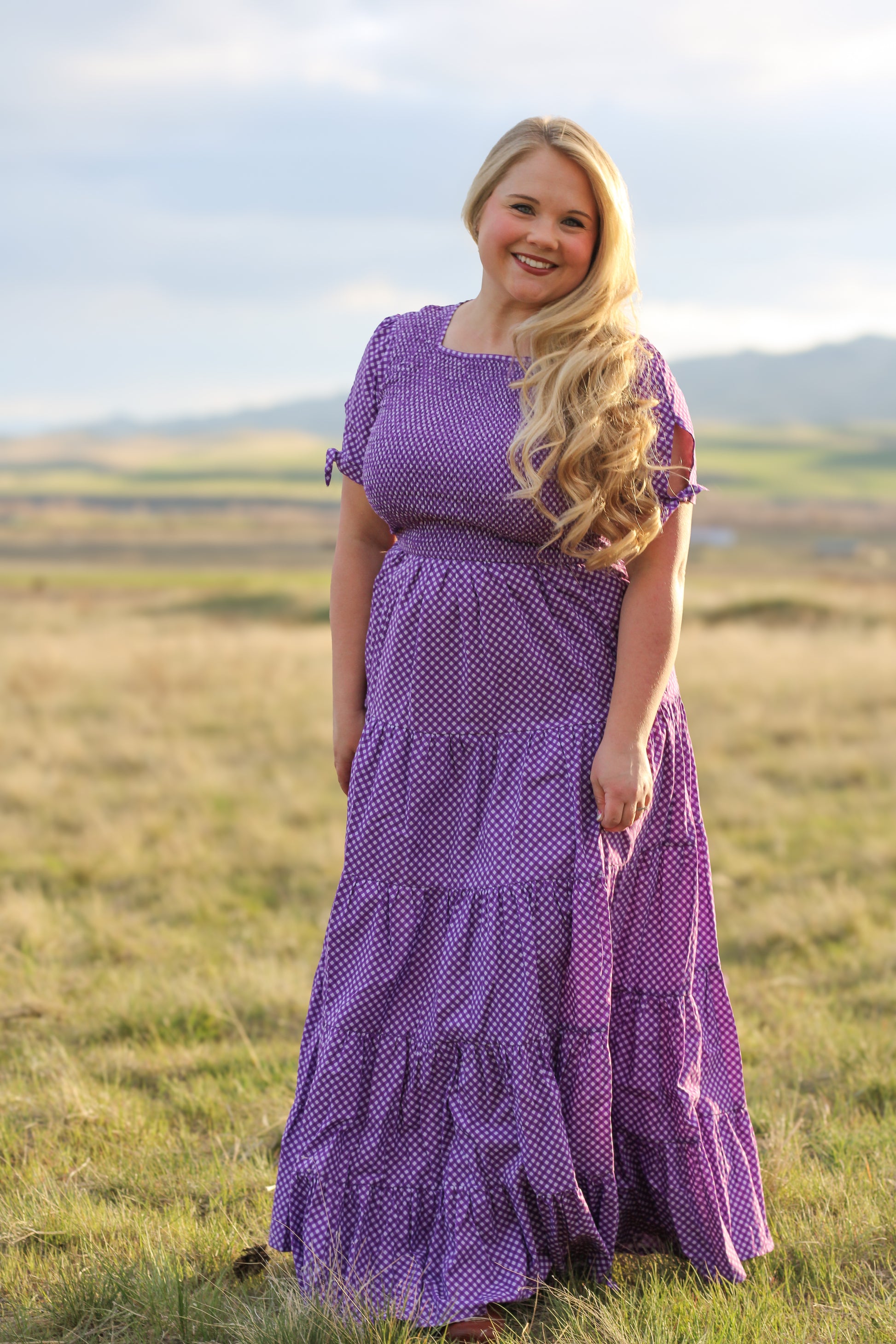 A woman wearing a purple, gingham, five-tiered maxi modest nursing dress