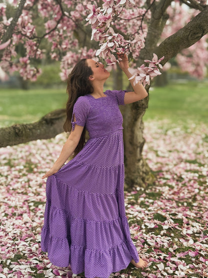 A woman wearing a purple, gingham, five-tiered maxi modest nursing dress