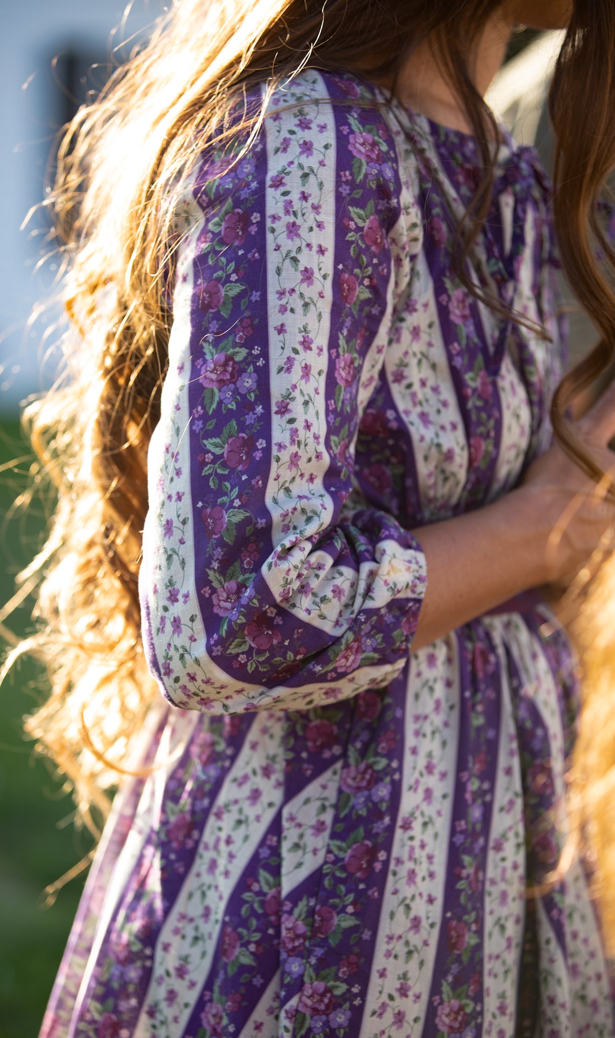 Close-up of a woman wearing a modest nursing purple floral dress with long hair.