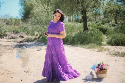A woman wearing a purple, gingham, five-tiered maxi modest nursing dress