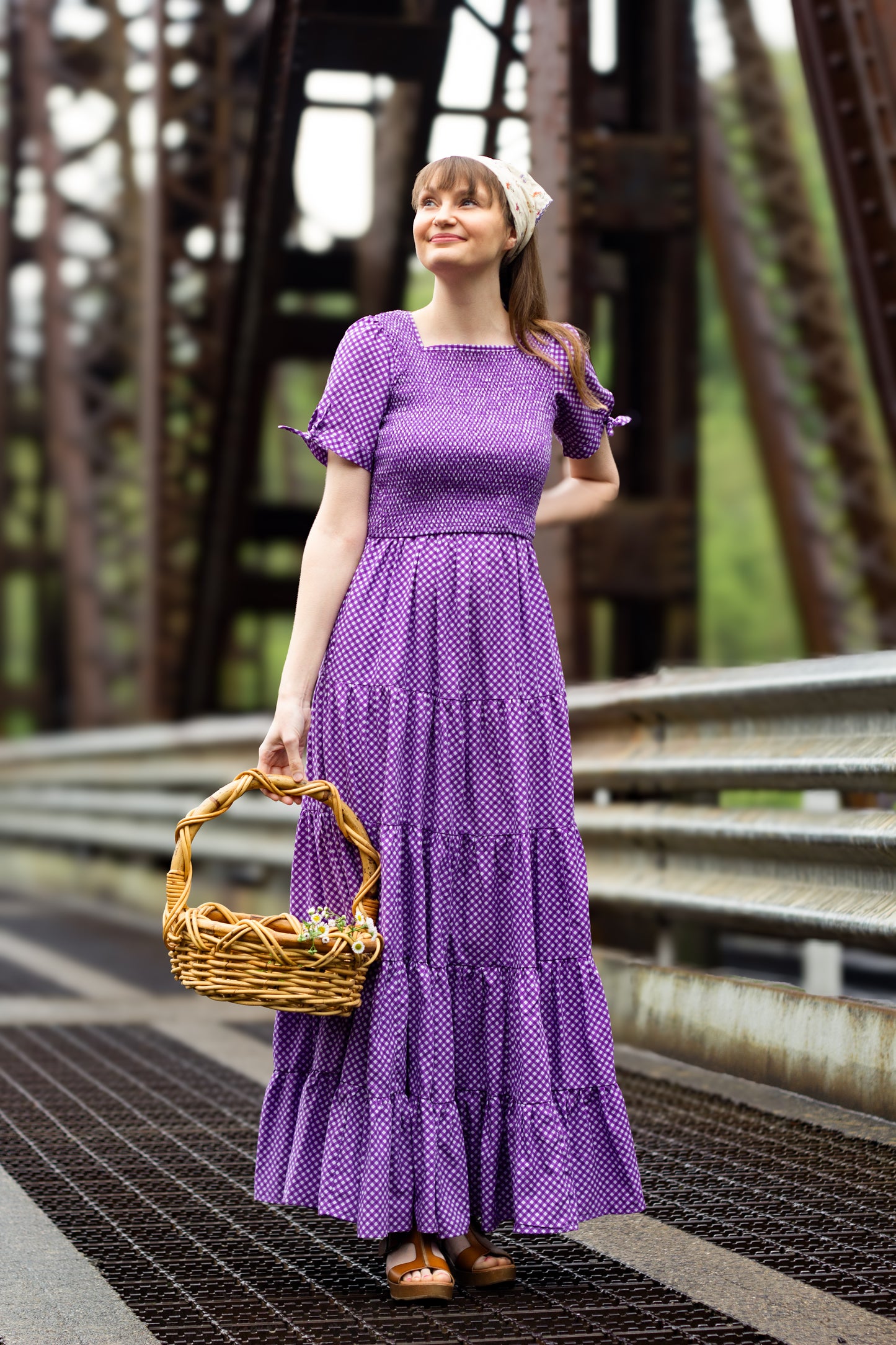 A woman wearing a purple, gingham, five-tiered maxi modest nursing dress