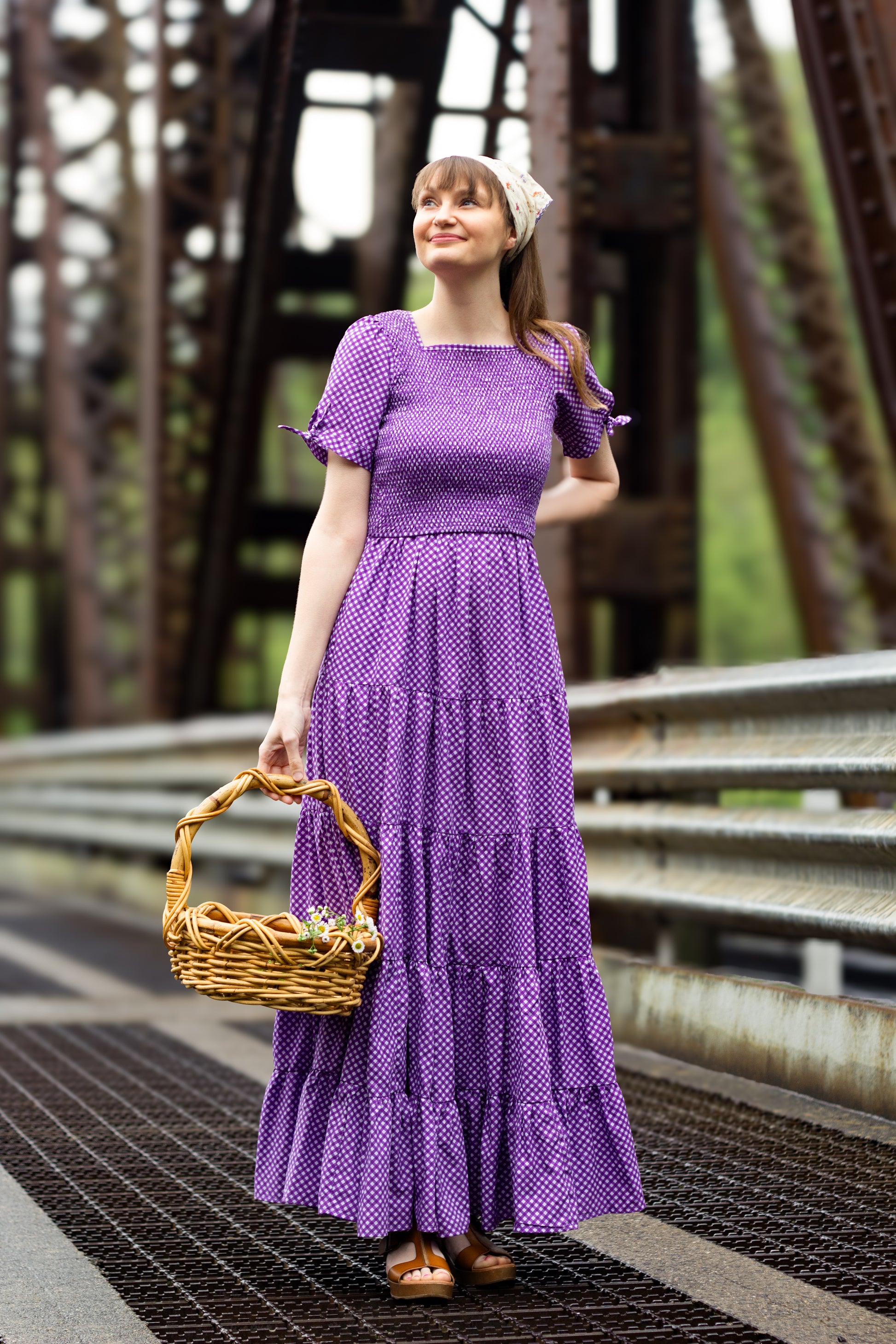 A woman wearing a purple, gingham, five-tiered maxi modest nursing dress