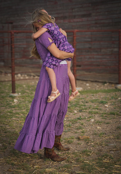 A woman wearing a purple, gingham, five-tiered maxi modest nursing dress with her daughter wearing a matching dress