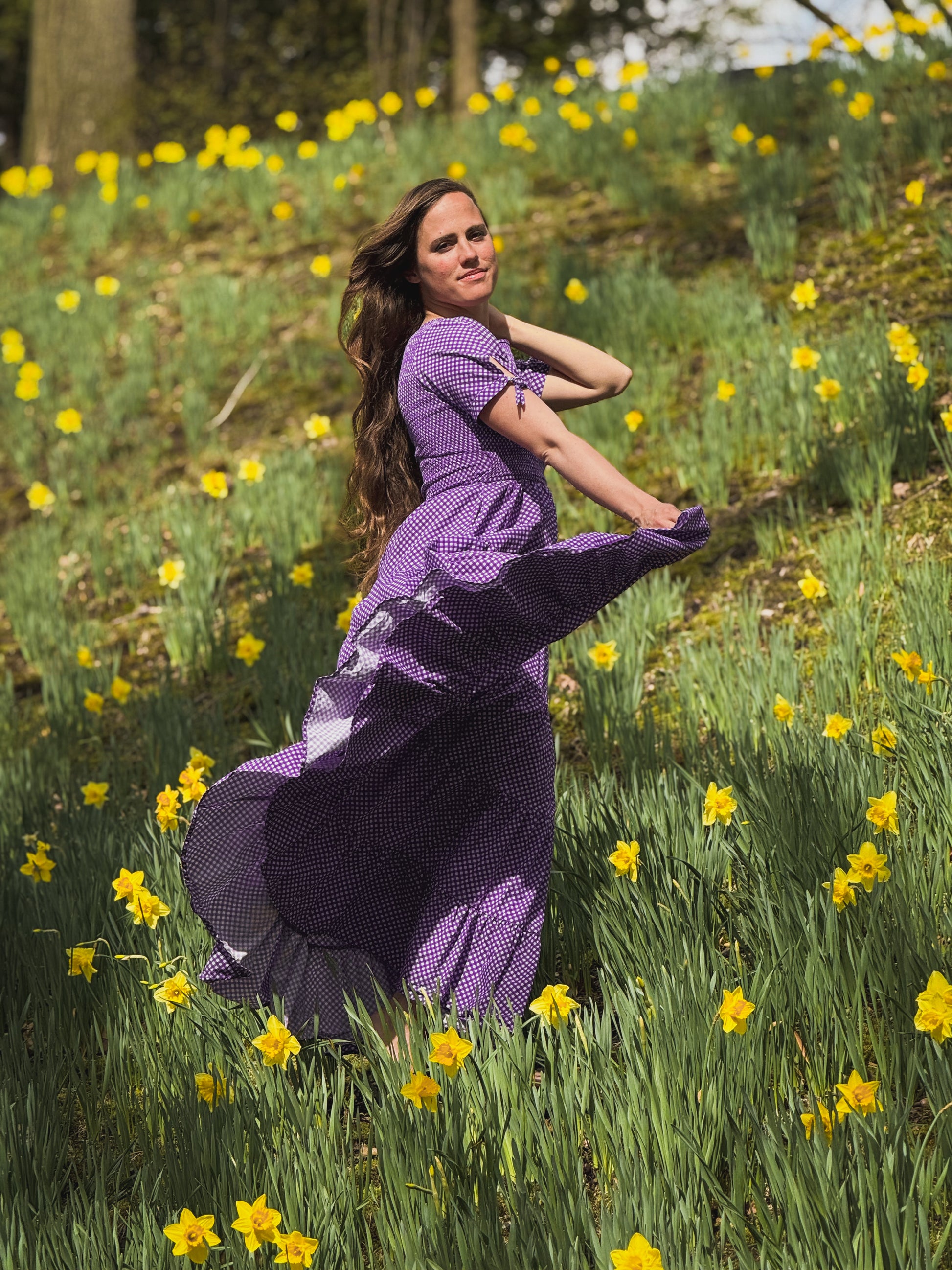 A woman wearing a purple, gingham, five-tiered maxi modest nursing dress