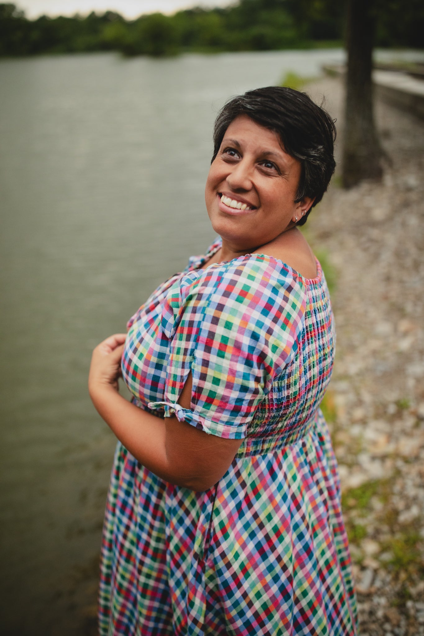Woman in a colorful modest nursing dress standing by a body of water